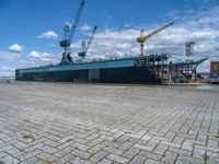 a large ship with crane on deck next to it in the water near docks and cranes