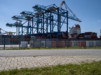 an industrial ship sits next to a large container ship in the distance at a dock