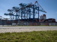 an industrial ship sits next to a large container ship in the distance at a dock