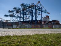 an industrial ship sits next to a large container ship in the distance at a dock