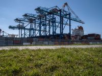 an industrial ship sits next to a large container ship in the distance at a dock