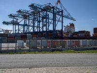 an industrial ship sits next to a large container ship in the distance at a dock