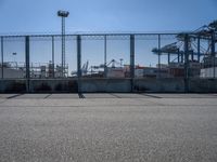 the container cranes are standing behind the barrierd area by the side of the road