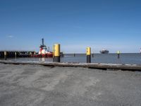 two tugboats docked at the beach in a dock near water and a large ship