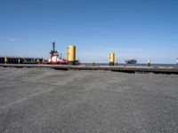 two tugboats docked at the beach in a dock near water and a large ship