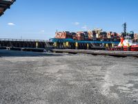 a long dock filled with lots of cargo boats and docked ships by the water or on a calm day