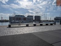 a paved patio overlooks a small dock in a port with several boats docked at a marina