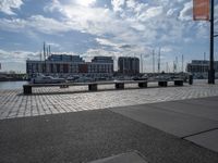 a paved patio overlooks a small dock in a port with several boats docked at a marina