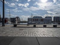 a paved patio overlooks a small dock in a port with several boats docked at a marina