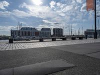 a paved patio overlooks a small dock in a port with several boats docked at a marina