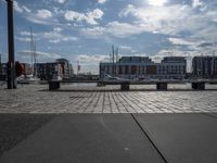 a paved patio overlooks a small dock in a port with several boats docked at a marina