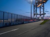 a long highway next to the large container lift bridge at dusk, with a truck on the roadway