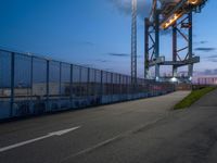 a long highway next to the large container lift bridge at dusk, with a truck on the roadway