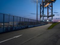 a long highway next to the large container lift bridge at dusk, with a truck on the roadway