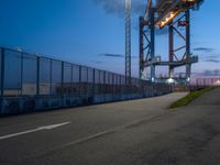 a long highway next to the large container lift bridge at dusk, with a truck on the roadway