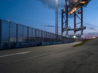 a long highway next to the large container lift bridge at dusk, with a truck on the roadway