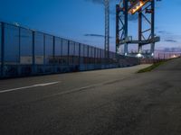 a long highway next to the large container lift bridge at dusk, with a truck on the roadway