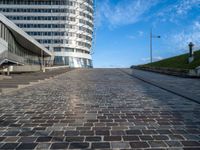 a paved stone walkway in front of a building on an island in the ocean on a sunny day