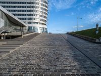 a paved stone walkway in front of a building on an island in the ocean on a sunny day