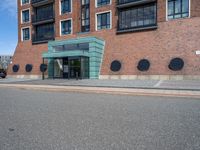 an empty street in front of a modern building with round windows on it and a sign hanging above the doorway