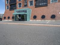 an empty street in front of a modern building with round windows on it and a sign hanging above the doorway