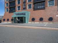 an empty street in front of a modern building with round windows on it and a sign hanging above the doorway