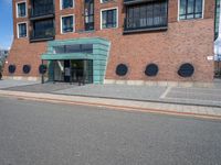 an empty street in front of a modern building with round windows on it and a sign hanging above the doorway