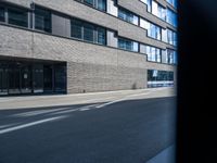 a building that has a few windows on the side walk and two traffic signs in front of it