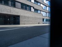 a building that has a few windows on the side walk and two traffic signs in front of it