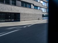 a building that has a few windows on the side walk and two traffic signs in front of it