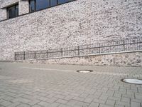 a young person standing on a brick path next to a wall with some stairs in the background