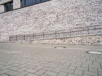 a young person standing on a brick path next to a wall with some stairs in the background