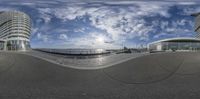 fisheye image of a wide angle looking down the street in front of buildings and a large body of water