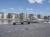 boats and apartments near the waterside in front of a dock with benches on top