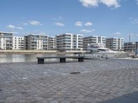 boats and apartments near the waterside in front of a dock with benches on top