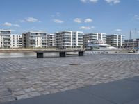 boats and apartments near the waterside in front of a dock with benches on top