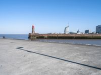 a view of the waterfront and buildings from the beach near a bench with a phone on it