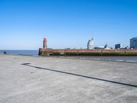 a view of the waterfront and buildings from the beach near a bench with a phone on it