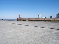 a view of the waterfront and buildings from the beach near a bench with a phone on it