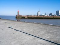 a view of the waterfront and buildings from the beach near a bench with a phone on it