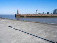 a view of the waterfront and buildings from the beach near a bench with a phone on it