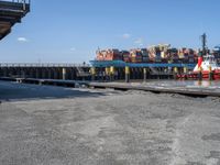 a boat is docked in the water near a dock and dockside with many containers on it