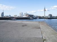 a bike parked on a cement sidewalk next to the water in front of large buildings