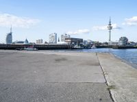 a bike parked on a cement sidewalk next to the water in front of large buildings