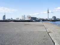 a bike parked on a cement sidewalk next to the water in front of large buildings