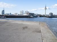 a bike parked on a cement sidewalk next to the water in front of large buildings