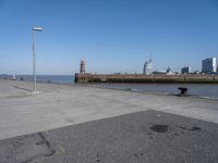 a view of a lighthouse, water and a walkway in the middle of a city