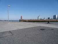 a view of a lighthouse, water and a walkway in the middle of a city