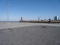 a view of a lighthouse, water and a walkway in the middle of a city