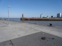 a view of a lighthouse, water and a walkway in the middle of a city